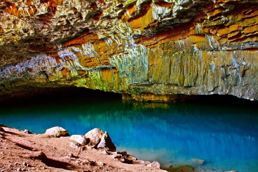 Exploring the caves on Kauai is one of the best things to do in Hanalei for people who love adventure. Image of the Blue Hole (aka Waikanaloa Cave) in North Shore Kauai.