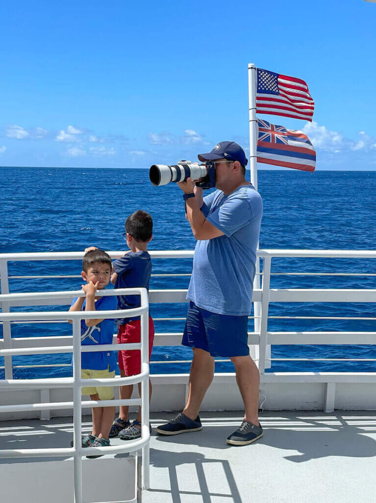 This Waikiki boat ride from the Atlantis submarine ride is short but awesome! Image of a dad taking photos while two young boys watch the water.