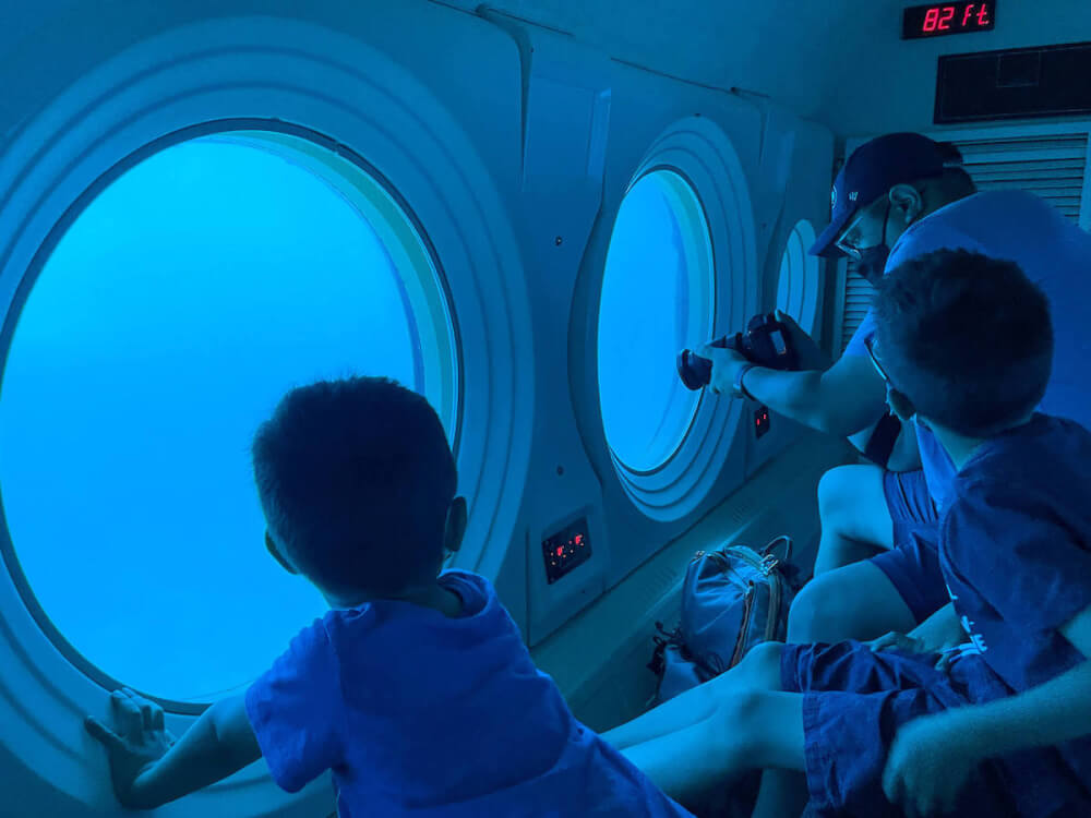Image of a family looking through the windows of the Waikiki Atlantis Submarine.