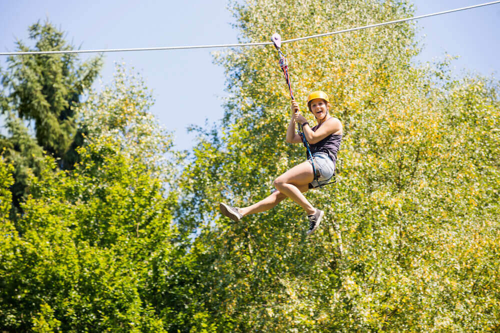 Find out where to go ziplining on Maui by top Hawaii blog Hawaii Travel with Kids. Image of a woman smiling on a zipline.