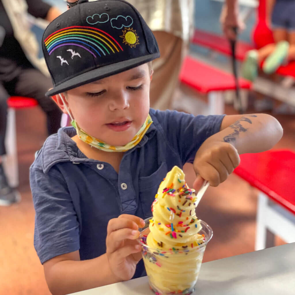 Yes, you can get Dole Whip at Pearl Harbor. Image of a boy eating Dole Whip with sprinkles.