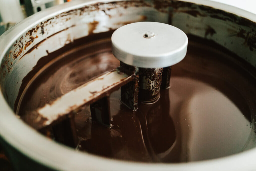 Image of cocoa being processed into chocolate in a big machine. Photo credit: Hawaii Tourism Authority (HTA) / Heather Goodman 