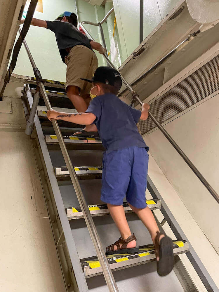 If you're visiting Pearl Harbor with kids, keep in mind that the stairs aboard the USS Battleship Missouri are steep. Image of two boys climbing a very steep staircase.