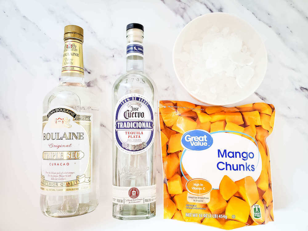 These are the ingredients you'll need to make frozen mango margaritas. Image of tequila, triple sec, a bag of frozen mango chunks, and a bowl of ice.