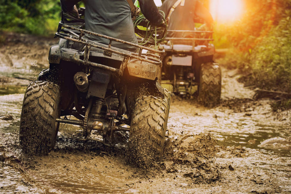 Image of two ATVs driving through mud.