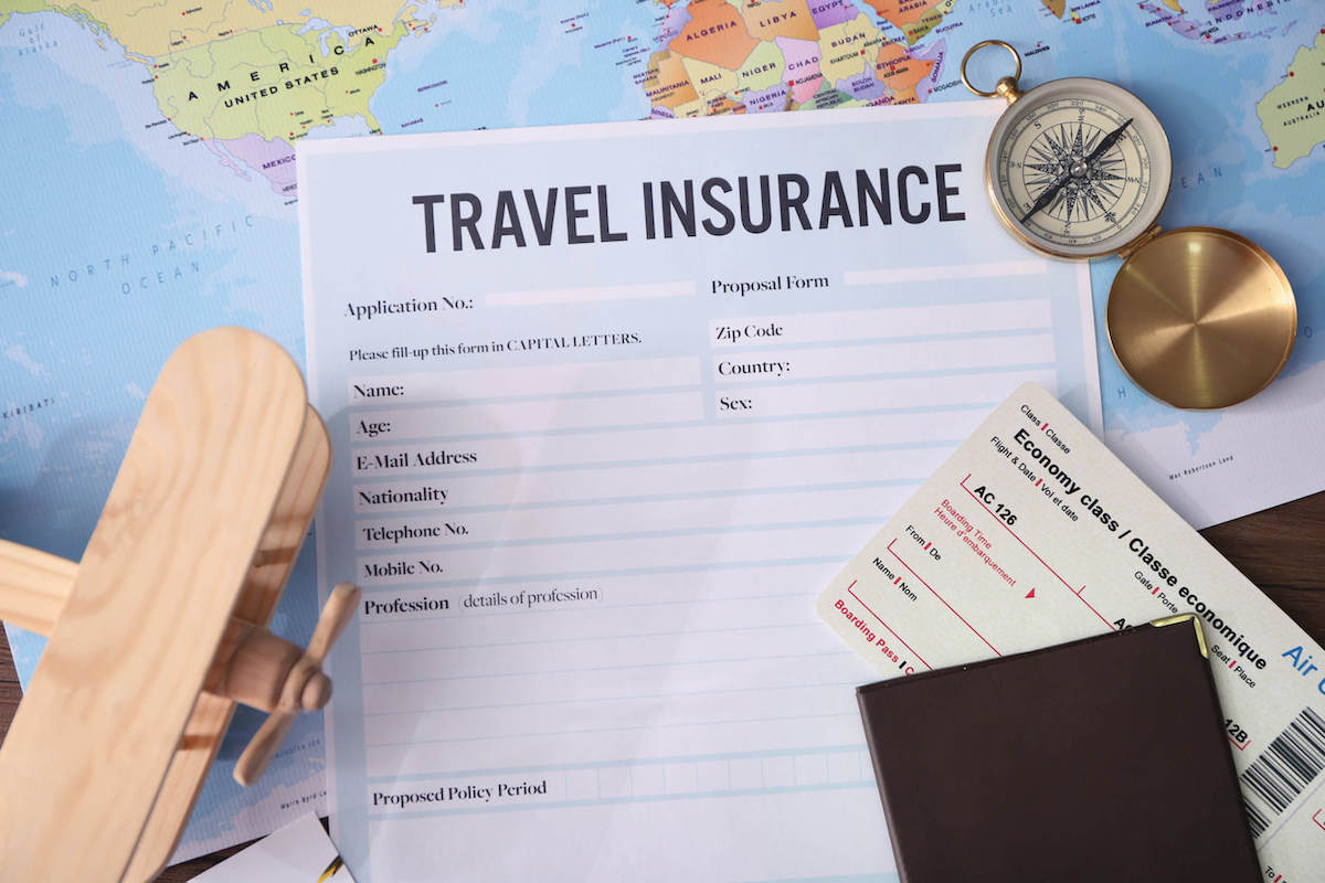 Find out whether or not you really need Hawaii travel insurance by top Hawaii blog Hawaii Travel with Kids. Image of some travel insurance paperwork on top of a map.