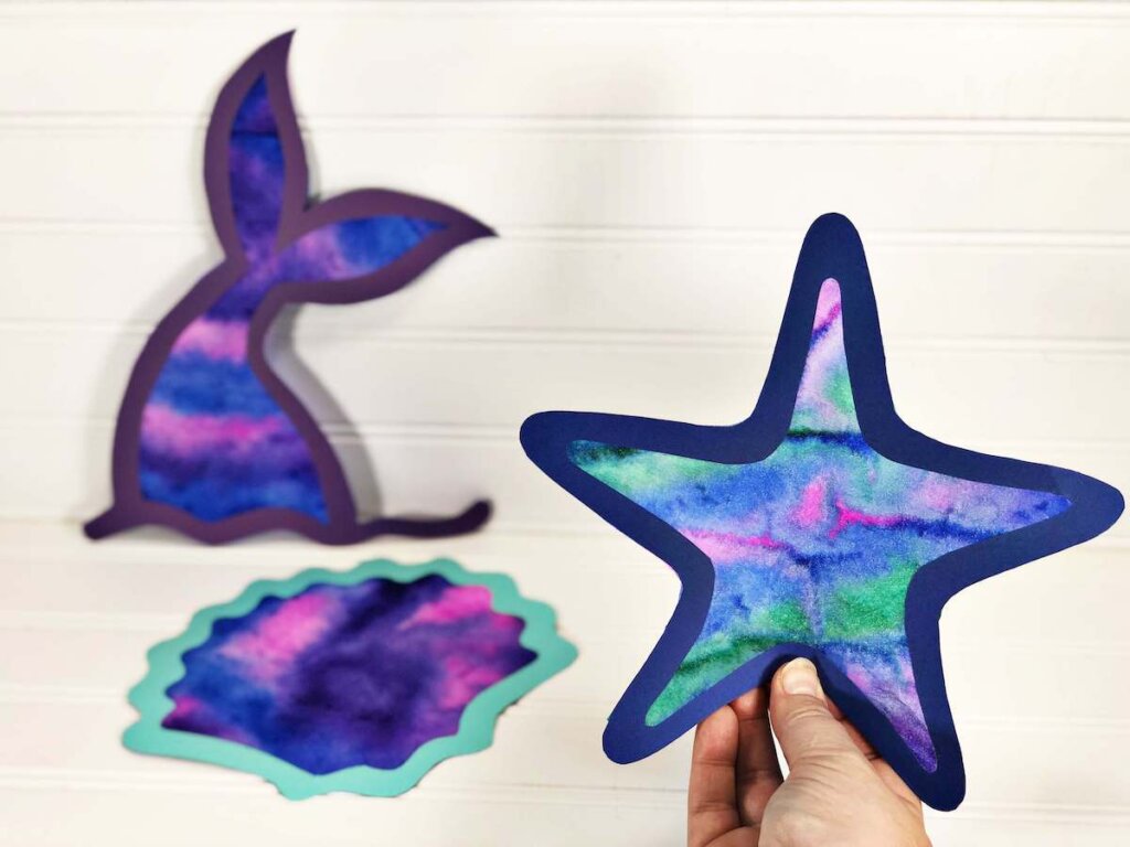 Find out how to make ocean animal coffee filter suncatchers by top Hawaii blog Hawaii Travel with Kids. Image of a starfish, memaid tail, and seashell suncatcher.