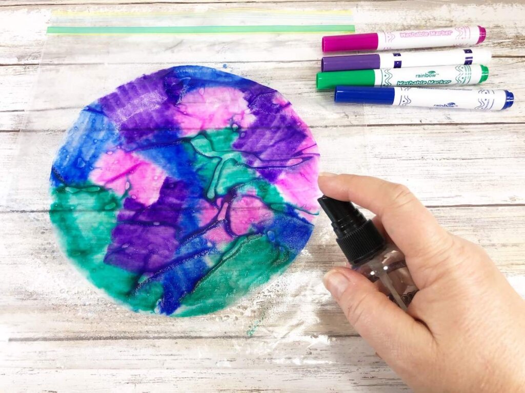 Image of someone misting a colorful coffee filter with a little spray bottle.