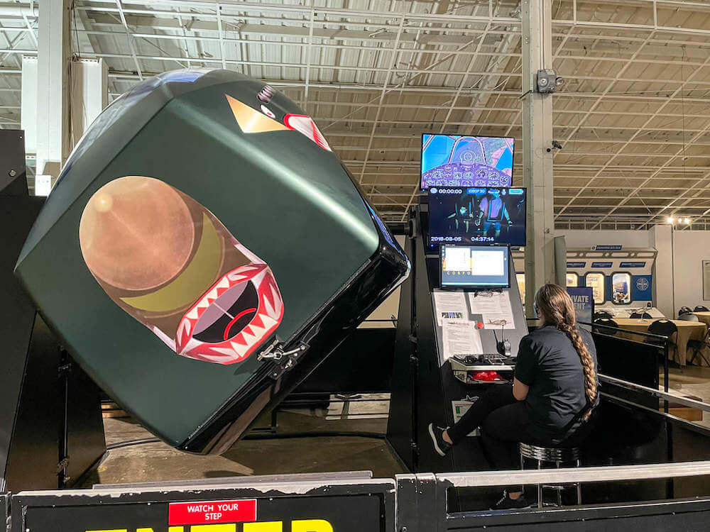 There are really cool Fighter Ace 360 flight simulators at the Pearl Harbor Aviation Museum. Image of a woman running the flight simulator.