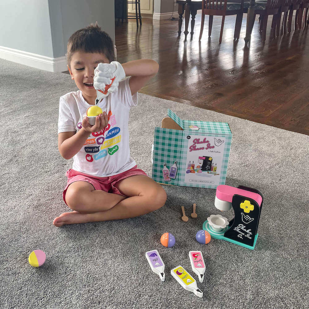 One of the cutest Hawaiian wooden food toys is this shave ice play set by Keiki Kaukau. Image of a boy using a wooden shave ice play set.