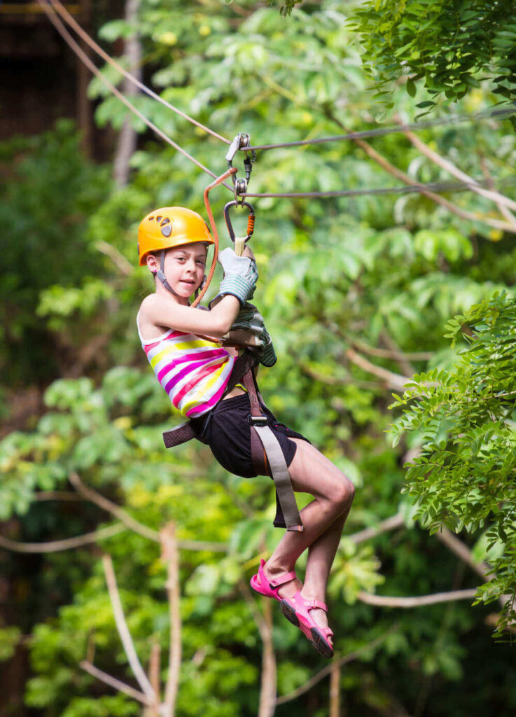 Find out my top tips for ziplining in Hawaii for beginners. Image of a girl ziplining in the jungle.