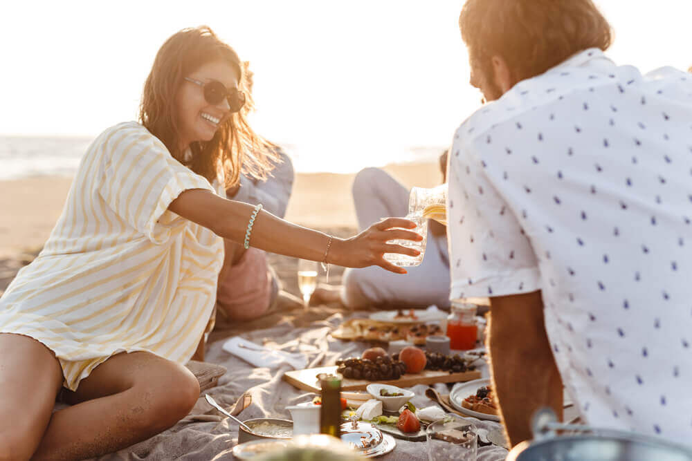 Image of people enjoying a beach picnic at sunset.