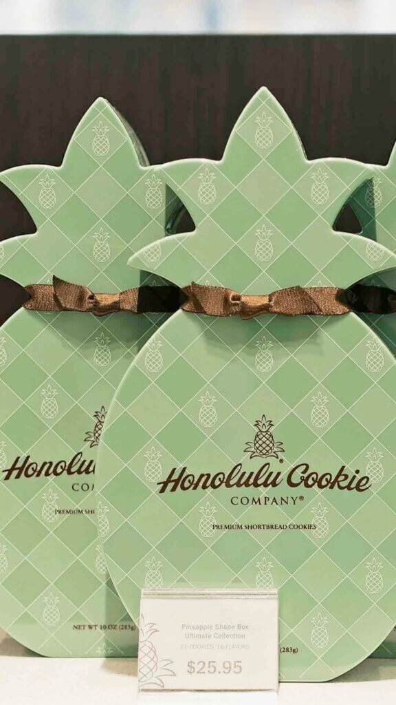 One of the best places to buy Hawaiian souvenirs online is Honolulu Cookie Company. Image of two Honolulu Cookie Company pineapple shaped boxes.