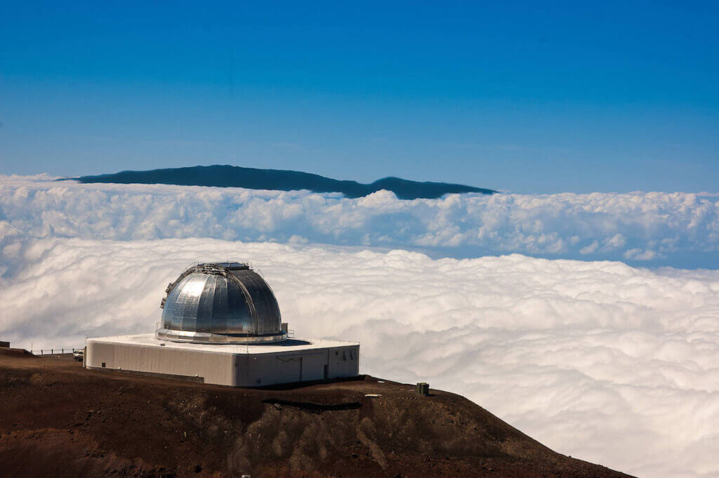 Image of the Mauna Kea Observatory surrounded by a field of snow.