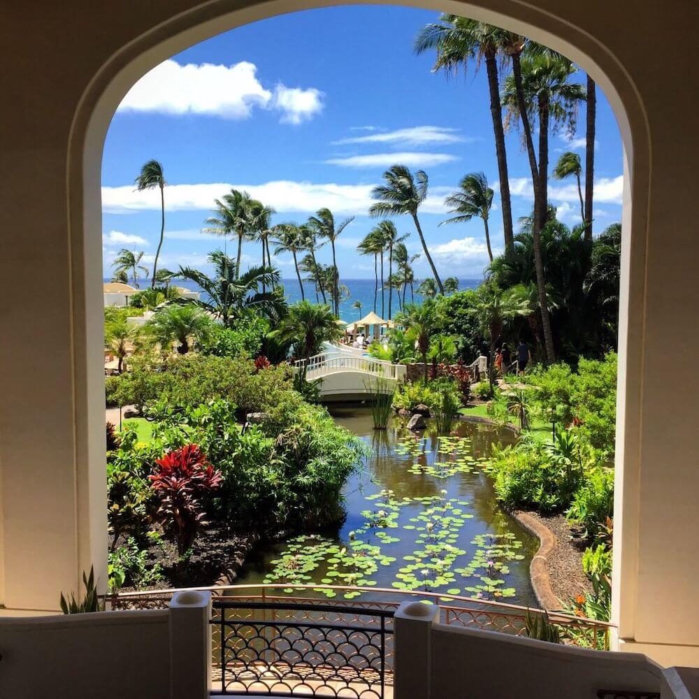 Image of the view out of the window of the Fairmont Kea Lani that includes a stream with lily pads and a bridge.