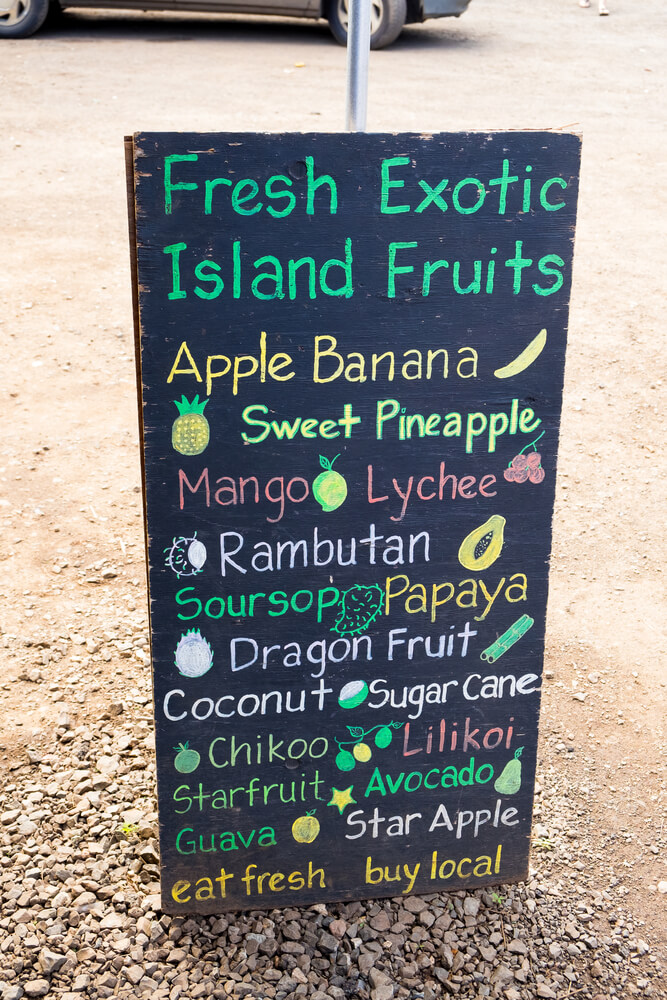 Find all kinds of amazing tropical fruit at an Oahu farmers market. Image of a sign listing fruit like lychee, mango, lilikoi, and more.