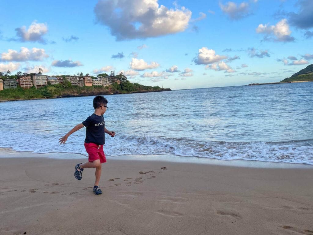 Where to stay on Kauai with kids: Royal Sonesta Kauai review. Image of a boy running on a beach in Hawaii.