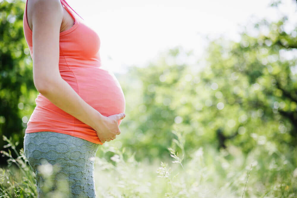 Image of a woman wearing a pink maternity tank top.