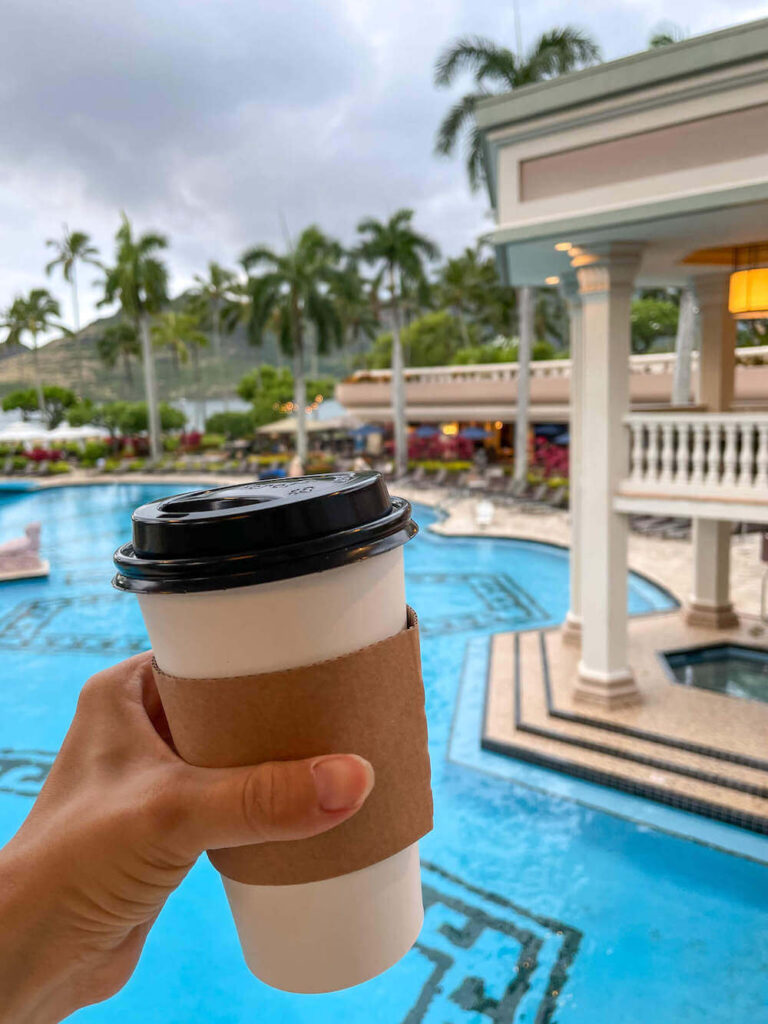 Where to stay on Kauai with kids: Royal Sonesta Kauai review. Image of a disposable coffee cup with a resort pool in the background.