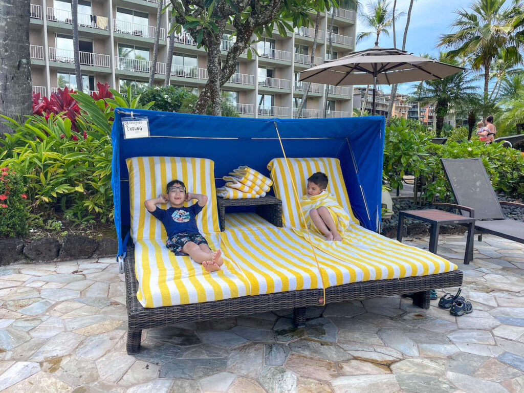 Where to stay on Kauai with kids: Royal Sonesta Kauai review. Image of two boys lounging in a cabana in Hawaii.