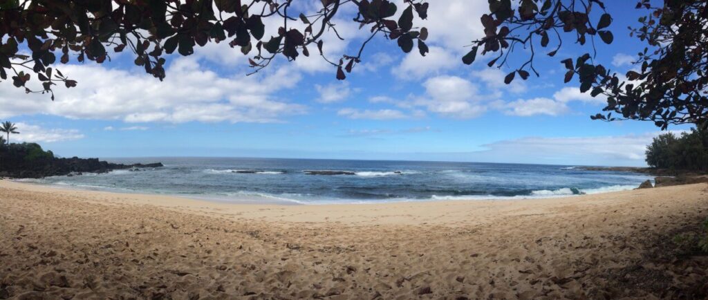 Another top Oahu snorkeling spot is Three Tables beach in North Shore Oahu. Image of a sandy beach and fairly calm water.