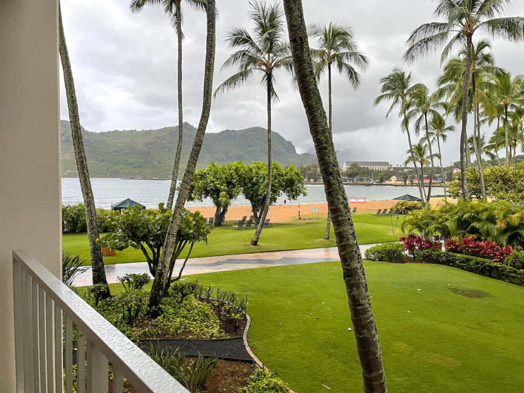 Where to stay on Kauai with kids: Royal Sonesta Kauai review. Image of a grassy area and Kalapaki Beach with mountains in background.