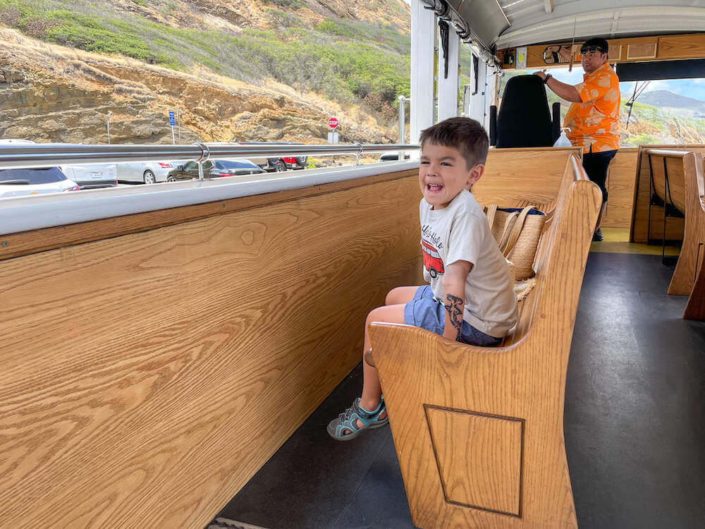 Image of a boy sitting in a wooden bench inside the Waikiki Trolley Blue Line.