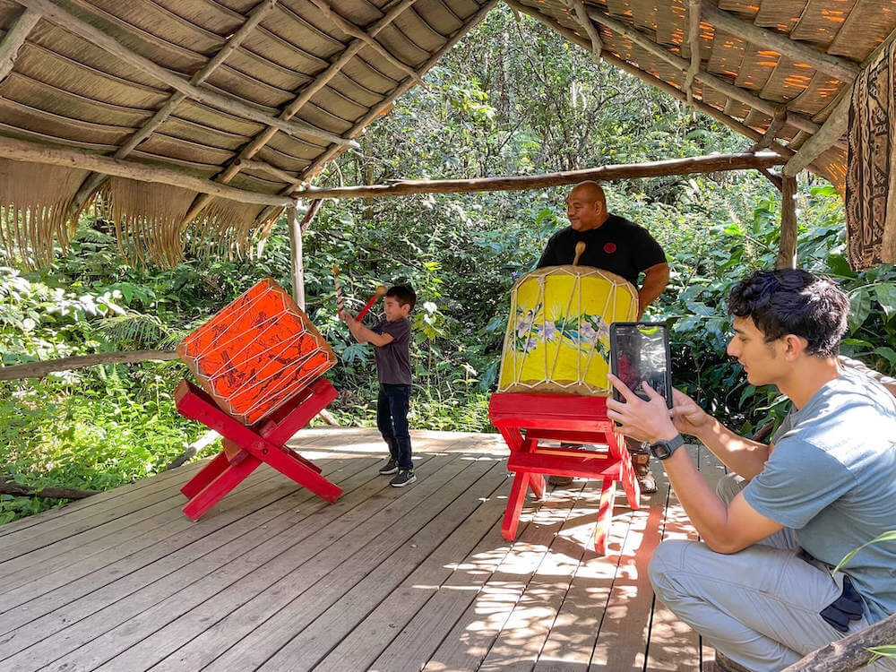 Image of a 5yo boy and a man playing large Tongan drums at the Aloha Adventure Farm on the Big Island of Hawaii.