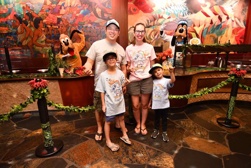 Image of a family posing for a photo with Chef Goofy and Pluto at Makahiki Restaurant at Disney Aulani Resort in Hawaii.