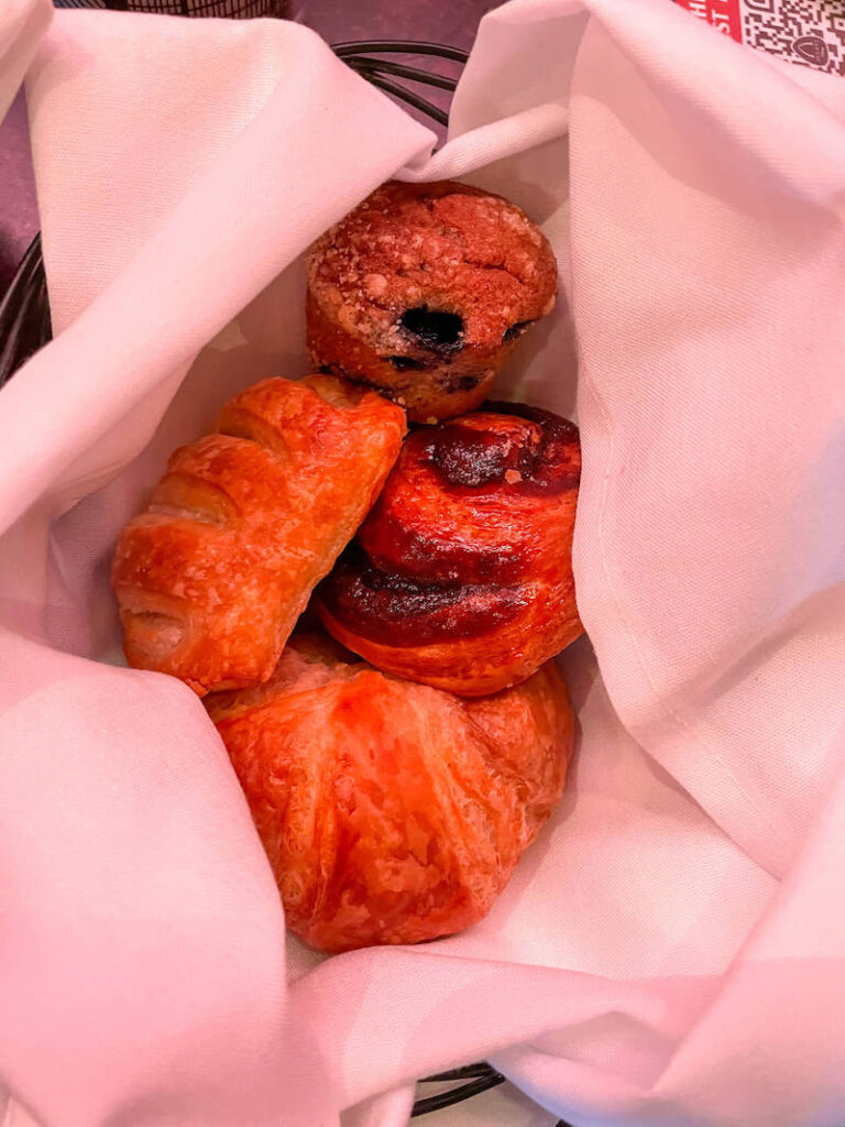 Image of a basket with a cloth napkin and 4 pastries inside.