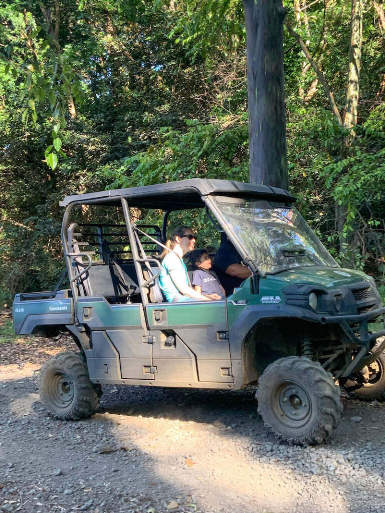 Image of a woman and 5yo boy riding in a green and black UTV on a Big Island ATV tour near Kona.