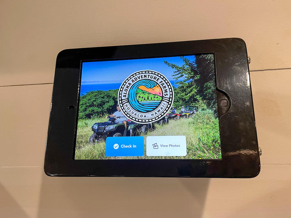 Image of an iPad attached to a wall with the Aloha Adventure Farms logo on it.