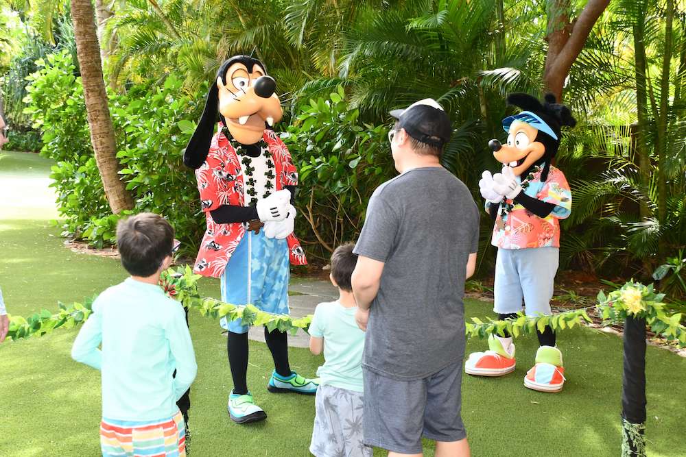 Image of a dad and two boys chatting with Goofy and Max.