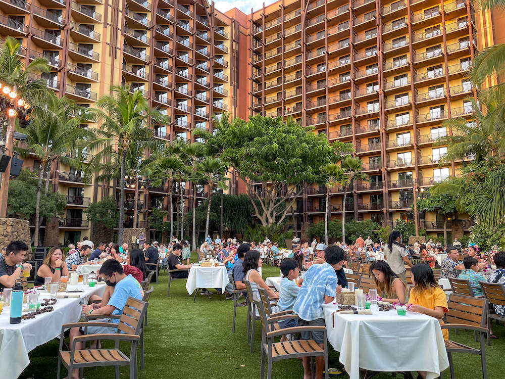 Image of a bunch of families sitting at tables on the grass at Disney Aulani Resort in Ko Olina