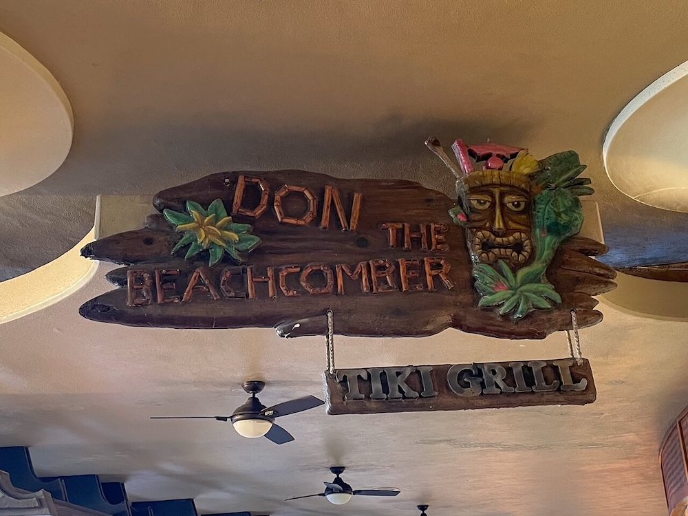 Image of a wooden sign with a tiki on it with text that reads Don the Beachcomber Tiki Grill.