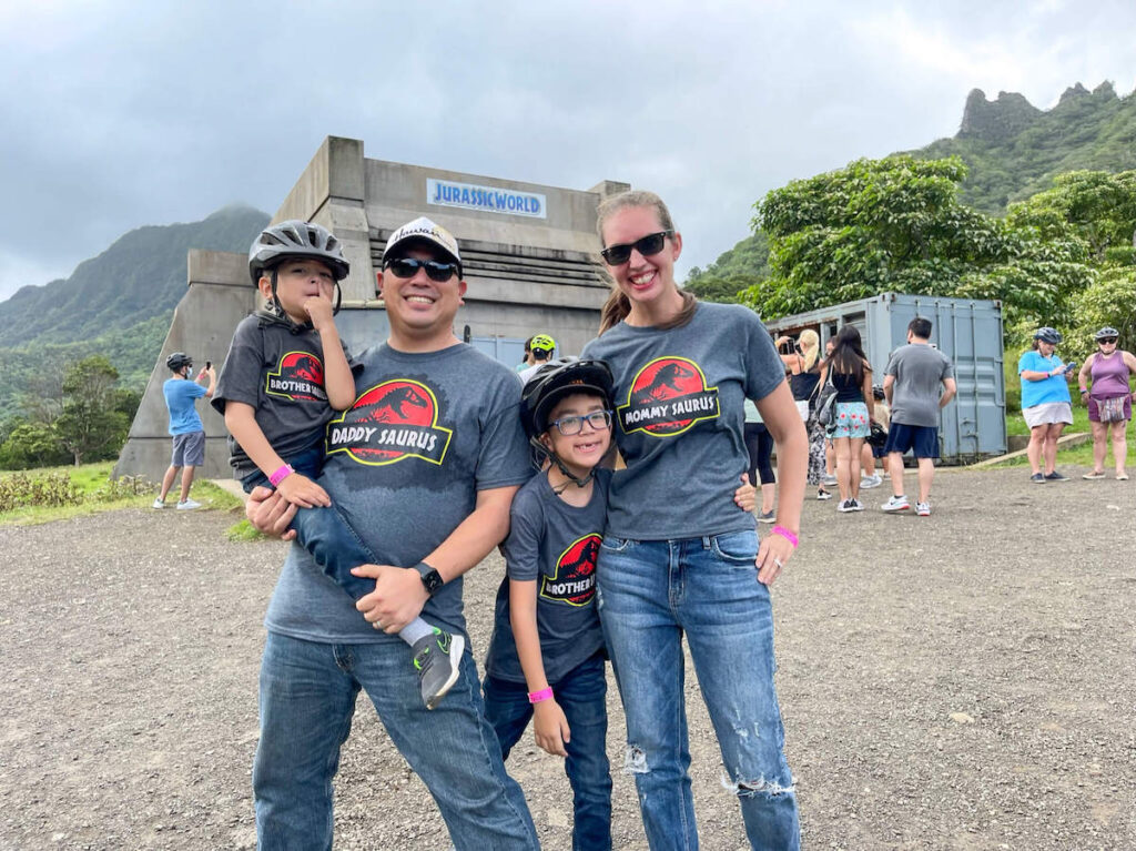 Image of a family wearing Jurassic Park shirts while standing at a Jurassic World movie site in Hawaii.