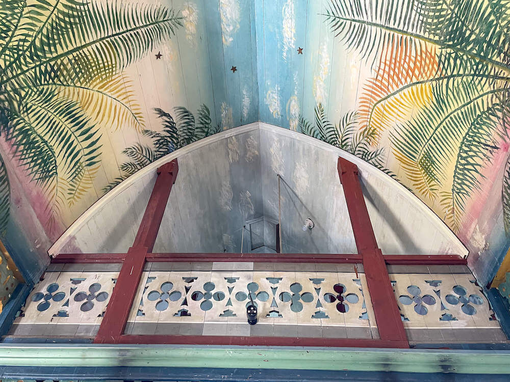 Image of a church ceiling painted with brightly colored palm tree leaves.