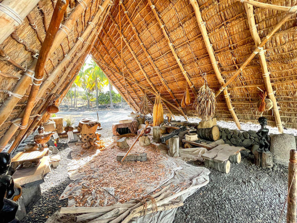 Image of the inside of  a Hawaiian thatched shelter filled with Ancient Hawaiian items.