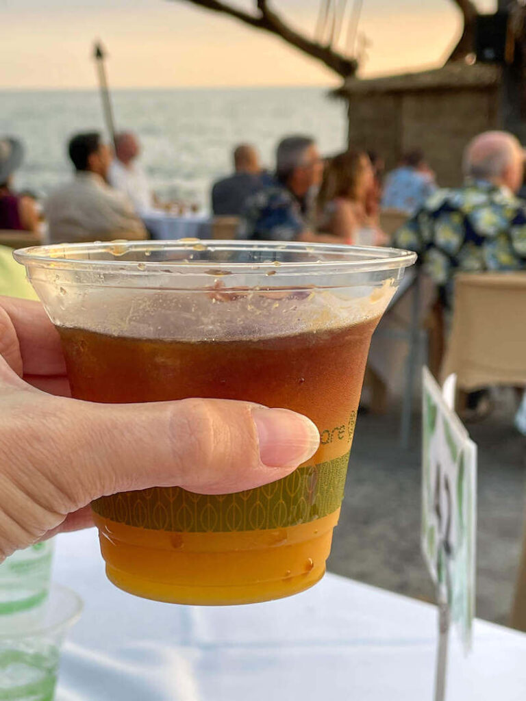 Image of a woman holding up a mai tai cocktail in a plastic cup at the Royal Kona luau on the Big Island of Hawaii.