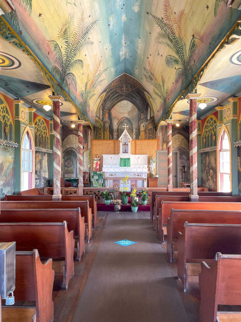 Image of the inside of St. Benedict's church where there are brightly colored religious paintings on the walls and ceiling.