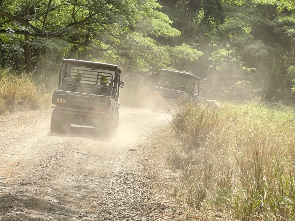 Image of two UTVs driving at Kualoa Ranch in Hawaii kicking up a ton of dust behind them.