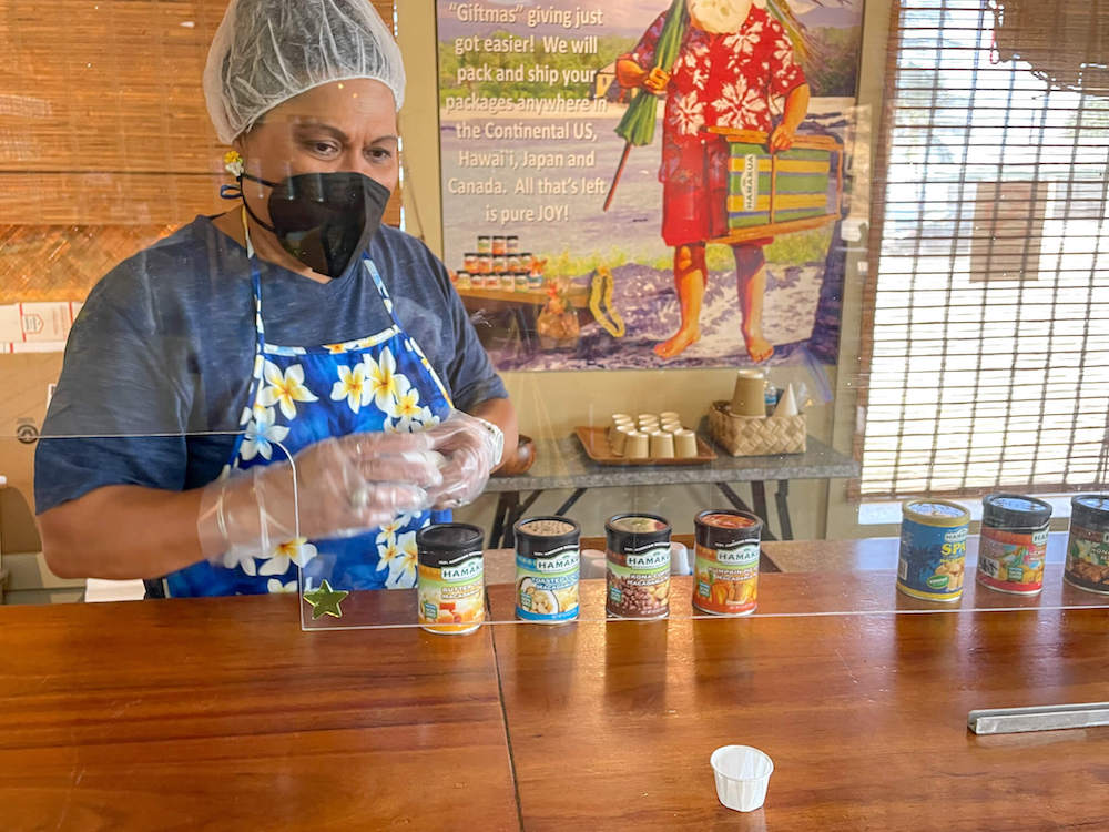 Image of a woman wearing a floral apron putting macadamia nuts in little containers for a Hawaiian macadamia nut tasting.