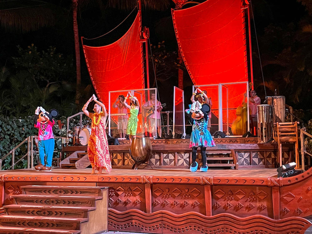 Image of Mickey and Minnie Mouse hula dancing with performers at the Disney Aulani luau on Oahu.