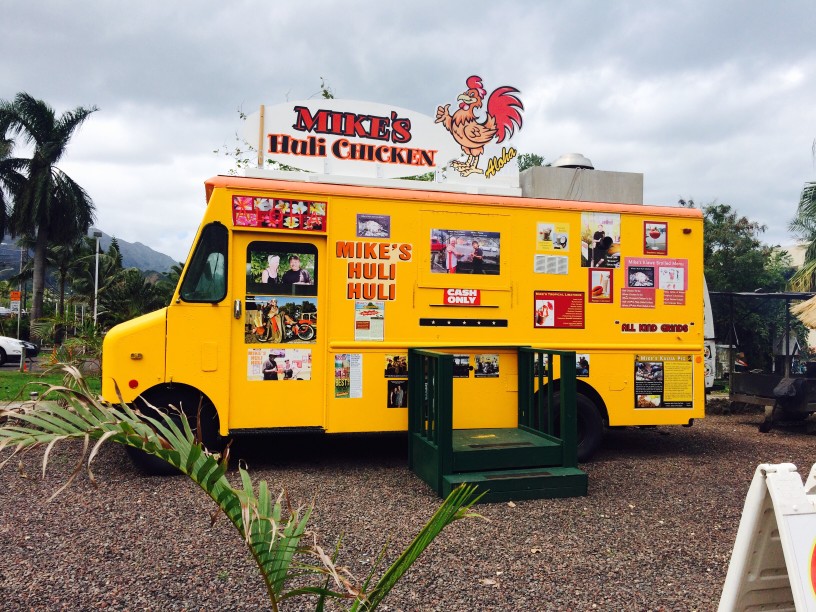 Image of a yellow food truck with the sign reading Mike's Huli Chicken and a cartoon rooster.