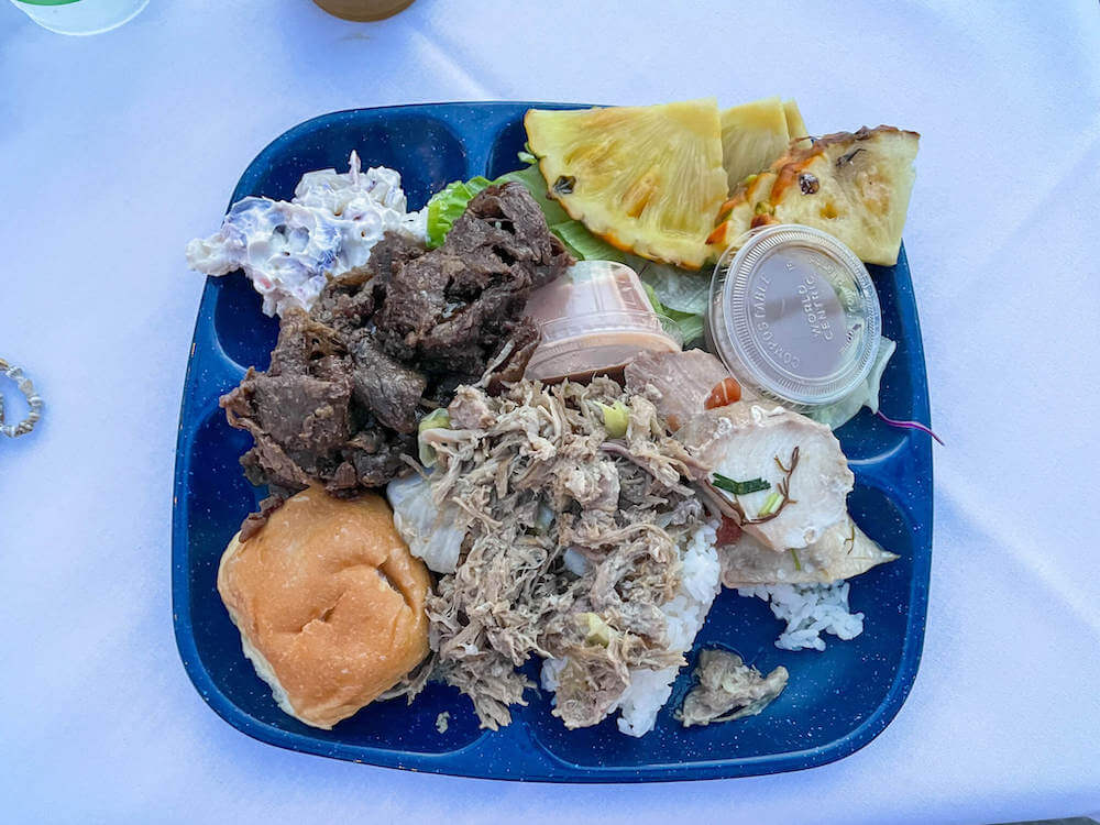 Image of a blue square plate with heaping piles of Hawaiian food on top.