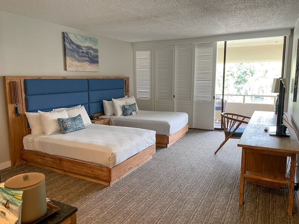 Image of a hotel room with 2 full beds, a large desk, and a large lanai.