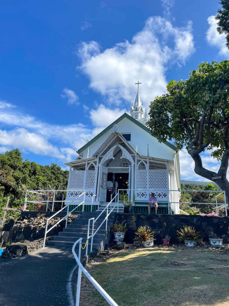 Image of a little white church in Hawaii with concrete stairs leading up to the open doors.