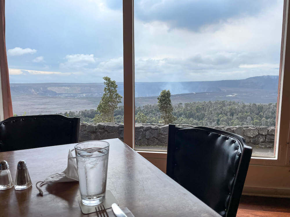 Image of a table in front of a large window with a volcano crater in the background.