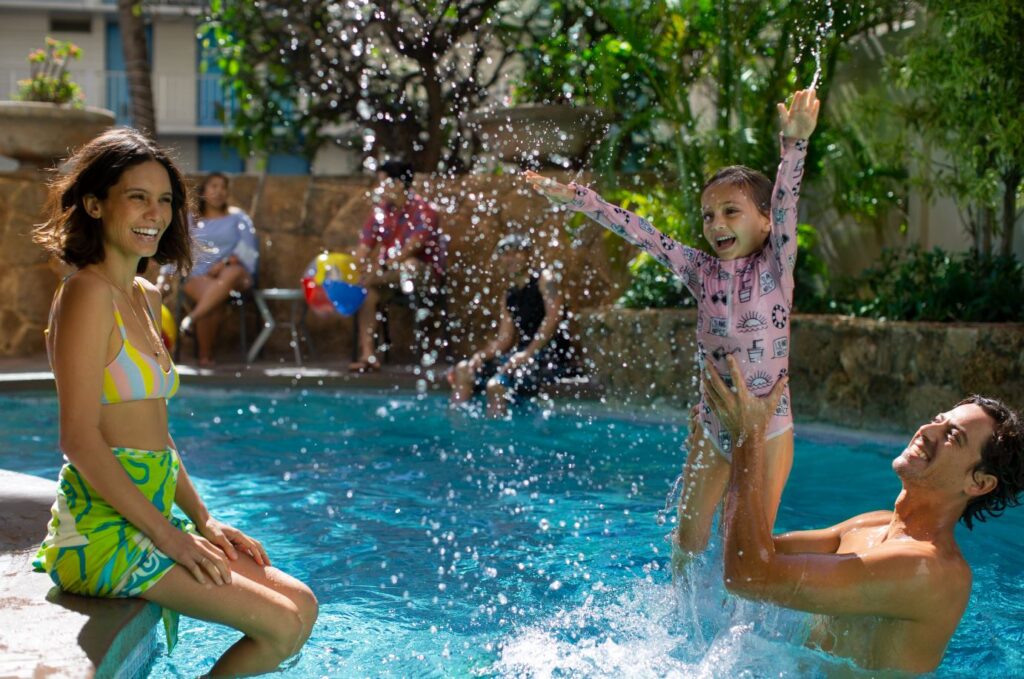 Image of a family playing in a swimming pool at the Coconut Waikiki Hotel on Oahu.