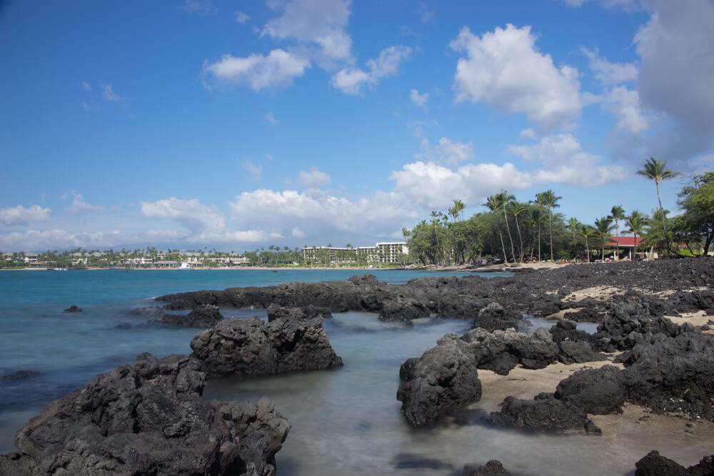 Image of lava rocks in the water at Anaeho'omalu Bay on the Big Island, one of the best kid friendly Big Island beaches.